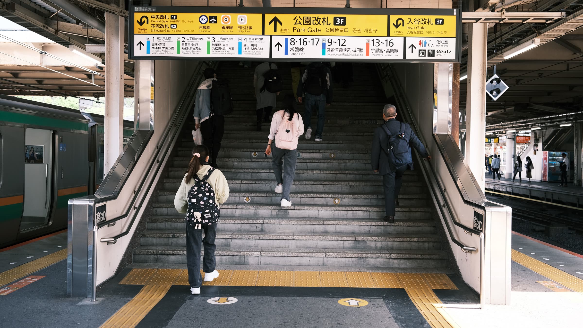 Commuters climbing station stairs under bilingual exit signs